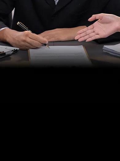Two people reviewing a printed contract on a clipboard across a desk