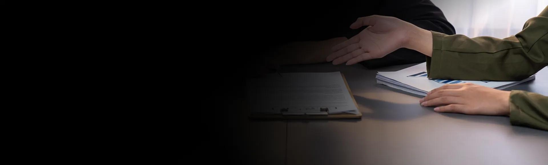 Two people reviewing a printed contract on a clipboard across a desk