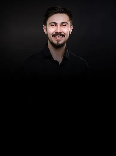 A smiling man giving two thumbs up against a black background